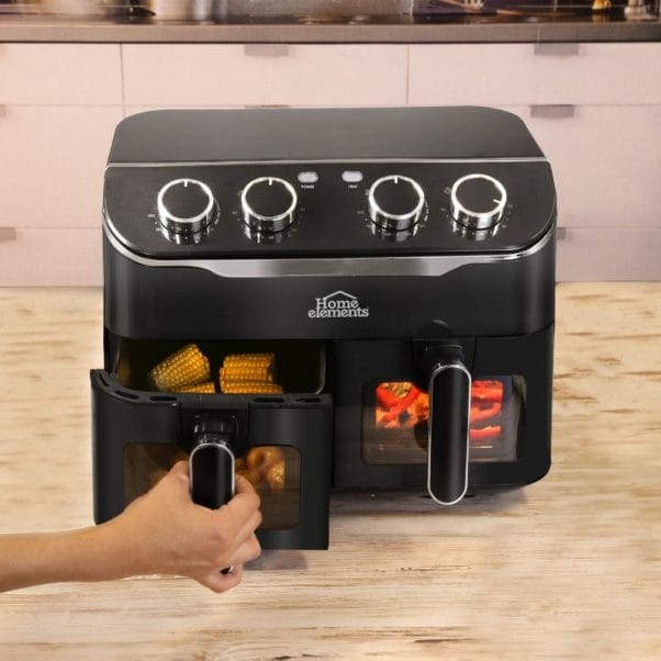 Una persona sostiene una freidora de aire negra (Freidora Aire 8 Litros Duo Fryer) sobre una mesa. Una persona sostiene una freidora de aire negra (Freidora Aire 8 Litros Duo Fryer) sobre una mesa.