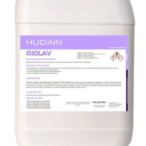 Un recipiente de plástico blanco con la etiqueta "Oxilav 20 litros - Blanqueador textil de peróxido de hidrógeno". La etiqueta, sobre un fondo violeta claro, incluye instrucciones de uso de la solución de peróxido de hidrógeno junto con advertencias de seguridad y símbolos de peligro.